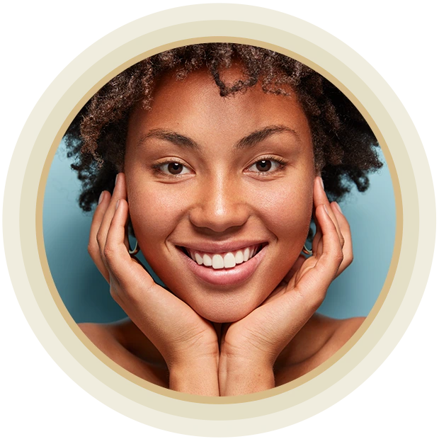 Close up portrait of relaxed black woman has gentle skin after taking shower, satisfied with new lotion, has no makeup, smiles tenderly, shows perfect teeth, stands shirtless against blue background