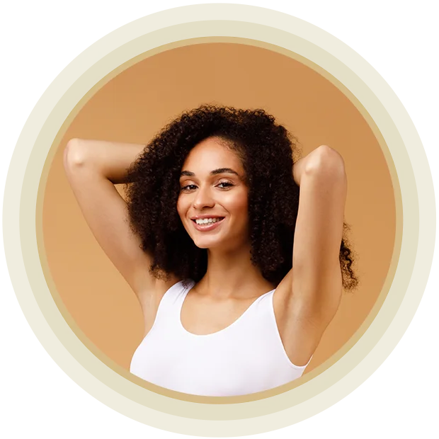 Sexy slender young woman wearing white lingerie and posing on beige studio background, raising arms up, smiling at camera. Lady with flat belly in underwear top bra and panties